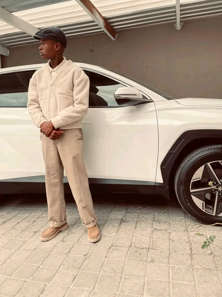 Dzana wearing a cream outfit beside a white car